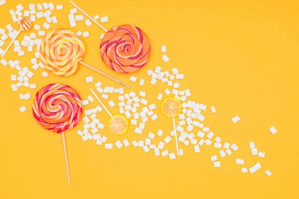 Vista superior de marshmallows espalhados e pirulitos isolados em laranja — Fotografia de Stock