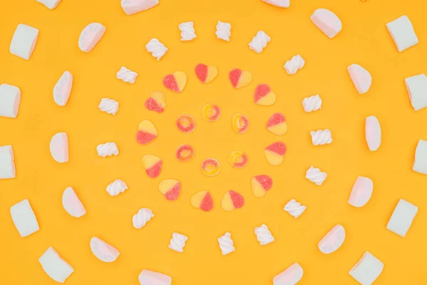 Top view of circles of yummy jelly candies and marshmallows isolated on orange — Stock Photo