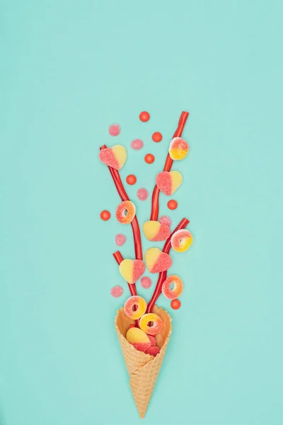 Vista dall'alto di caramelle alla gelatina con zucchero e cono di cialda isolato su turchese — Foto stock
