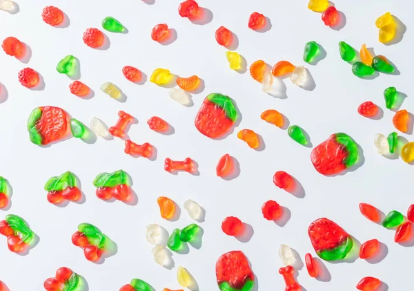 Vista elevada de sabrosos caramelos de gelatina dispersos en blanco - foto de stock