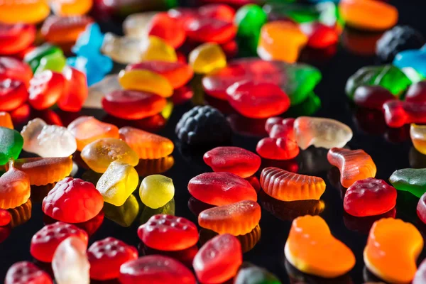 Caramelle di gelatina colorate diverse sulla superficie nera — Foto stock