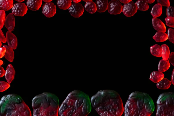 Top view of frame of jelly candies in shape of raspberries and strawberries isolated on black — Stock Photo