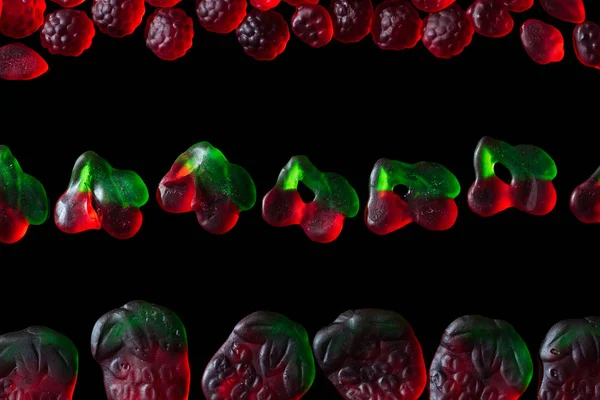 Top view of jelly candies in shape of raspberries, strawberries and cherries isolated on black — Stock Photo