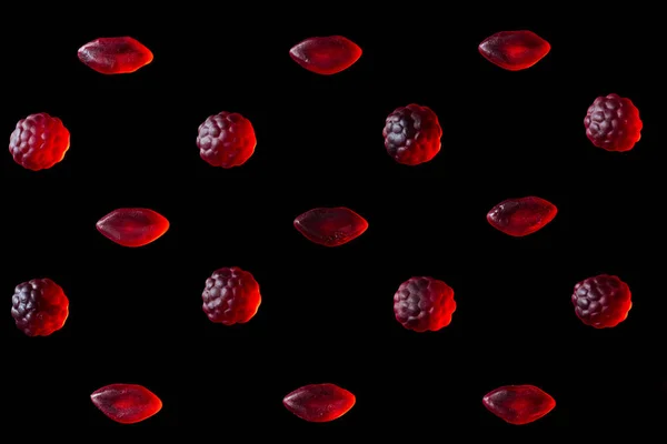 Conjunto de caramelos de jalea roja en forma de frambuesas y labios aislados en negro - foto de stock