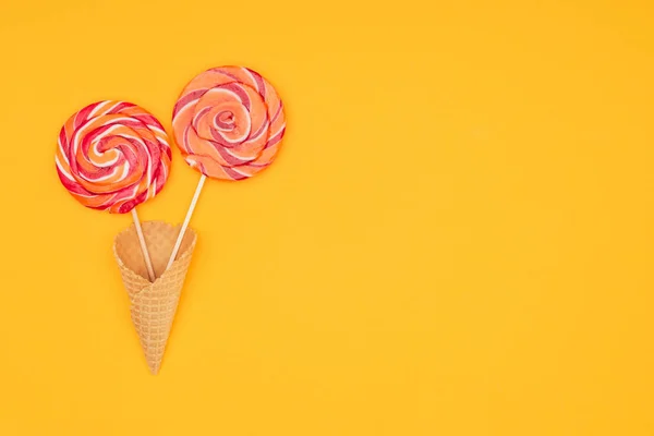 Top view of yummy round lollipops in waffle cone isolated on orange — Stock Photo