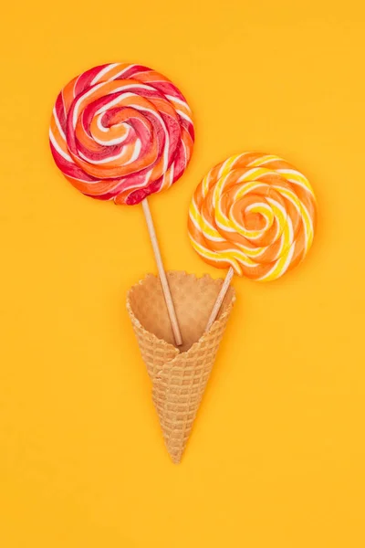 Top view of tasty round lollipops in waffle cone isolated on orange — Stock Photo