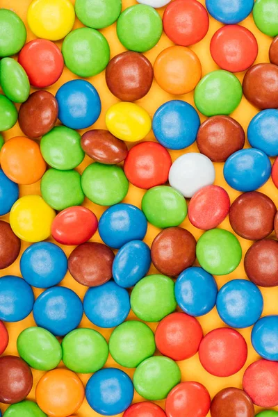 Top view of tasty bright dragee candies on yellow surface — Stock Photo