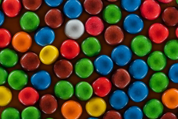 Vista superior de deliciosos caramelos dragee brillante en la superficie marrón - foto de stock