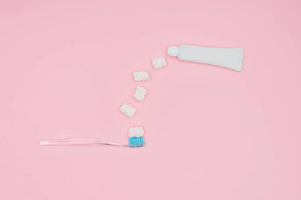 Top view of marshmallows, toothbrush and toothpaste tube isolated on pink — Stock Photo