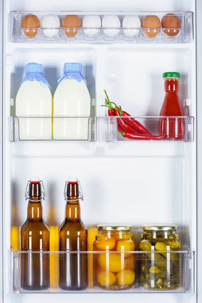 Huevos, botellas de leche y verduras conservadas en nevera - foto de stock
