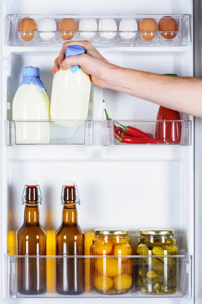 Обрізане зображення людини, що бере пляшку молока з холодильника — стокове фото