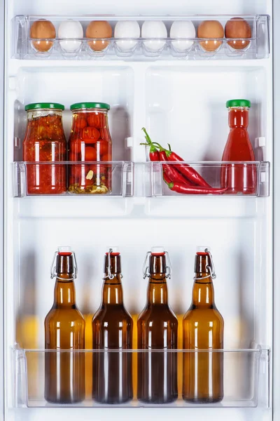 Œufs et bouteilles de bière en verre au réfrigérateur — Photo de stock