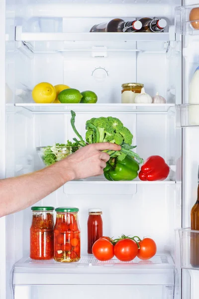 Cropped image of man taking broccoli from fridge — Stock Photo