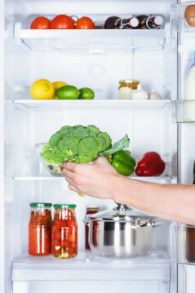 Imagen recortada del hombre tomando brócoli de la nevera - foto de stock