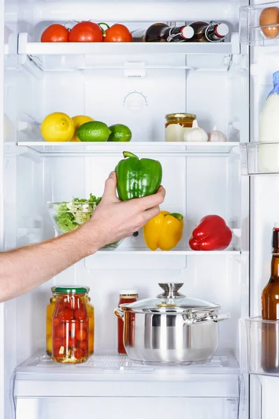 Abgeschnittenes Bild von Mann, der Paprika aus Kühlschrank nimmt — Stockfoto