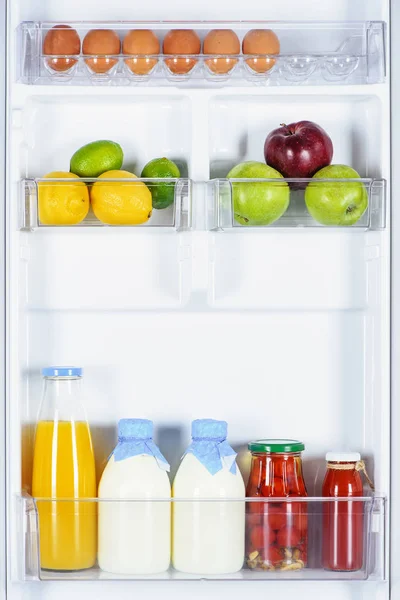 Apples, lemons, juice and milk in fridge — Stock Photo