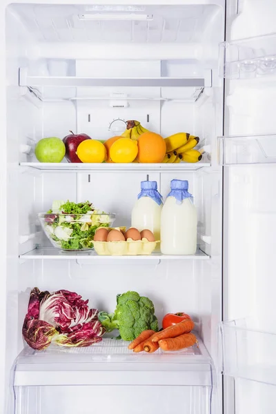 Fruits, vegetables and milk with eggs in fridge — Stock Photo