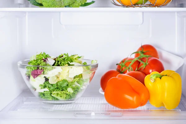 Schüssel Salat und reife Paprika im Kühlschrank — Stockfoto