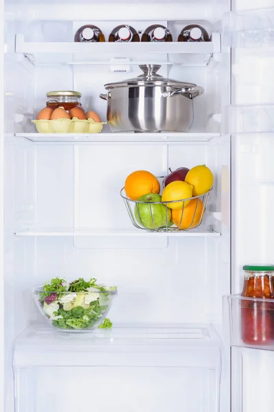 Fruits mûrs, salade, poêle et œufs au réfrigérateur — Photo de stock