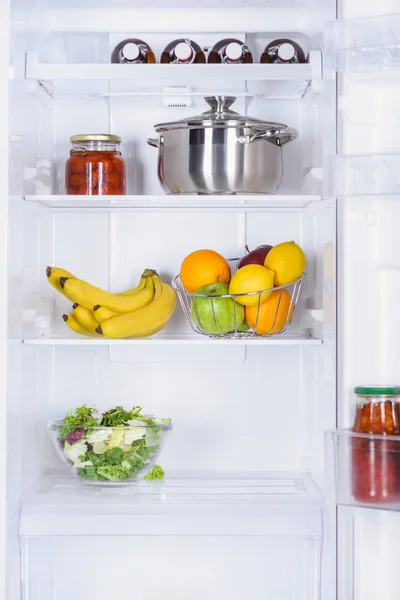 Reife Früchte, Salat, Pfanne und eingelegte Tomaten im Kühlschrank — Stockfoto