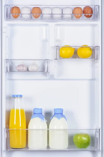 Eggs, garlic, lemons, juice and milk in fridge — Stock Photo