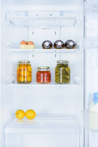 Lemons, preserved vegetables and eggs in fridge — Stock Photo