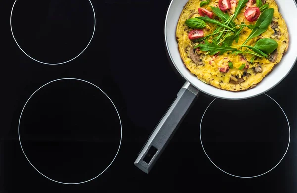 Top view of omelette in frying pan cooking on black stove — Stock Photo