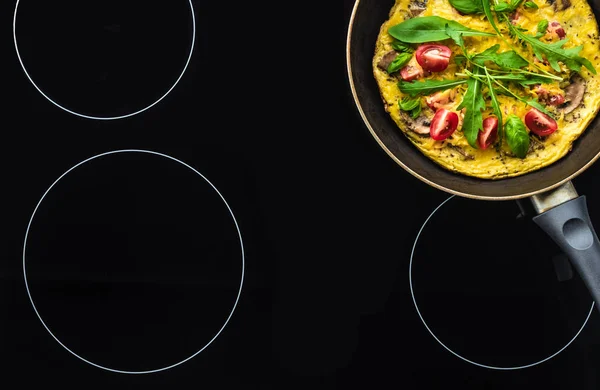 Вид сверху на омлет в сковороде приготовления пищи на черной плите — стоковое фото