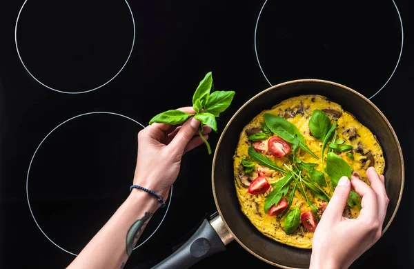 Tiro cortado de omelete mulher cozinhar na frigideira no fogão preto — Fotografia de Stock