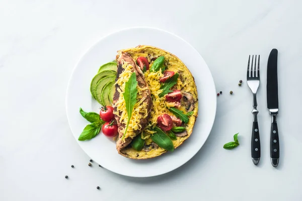 Vista superior de la tortilla saludable para el desayuno y cubiertos en la superficie de mármol blanco - foto de stock