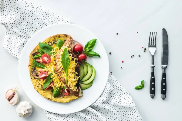 Vista superior de la tortilla para el desayuno y cubiertos en la superficie de mármol blanco - foto de stock