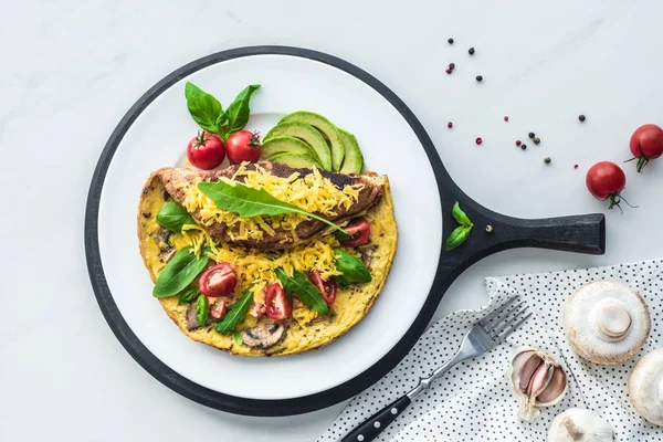 Food composition with healthy omelette on wooden board and fork on white marble tabletop — Stock Photo