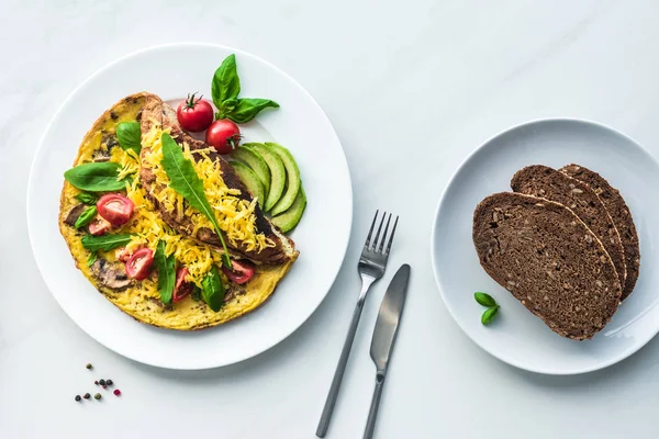 Blick von oben auf hausgemachtes Omelett und Brot zum Frühstück auf weißem Marmor — Stockfoto