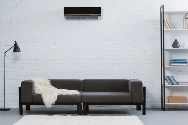 Modern air conditioner hanging on white brick wall at living room — Stock Photo