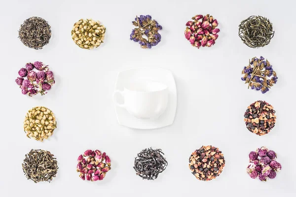 Top view of cup and plate in frame of dried herbal organic tea isolated on white — Stock Photo