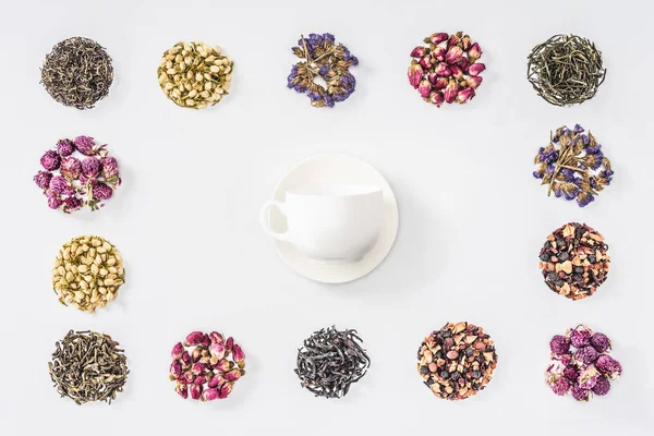Повышенный вид чашки и пластины в рамке сушеных травяной органический чай изолирован на белом — стоковое фото