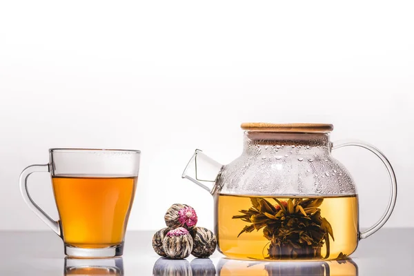 Cup and teapot of chinese flowering tea with tea balls on table — Stock Photo