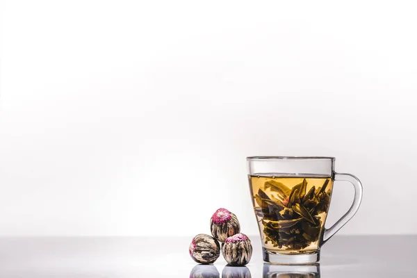 Cup of chinese flowering tea with tea balls on table — Stock Photo