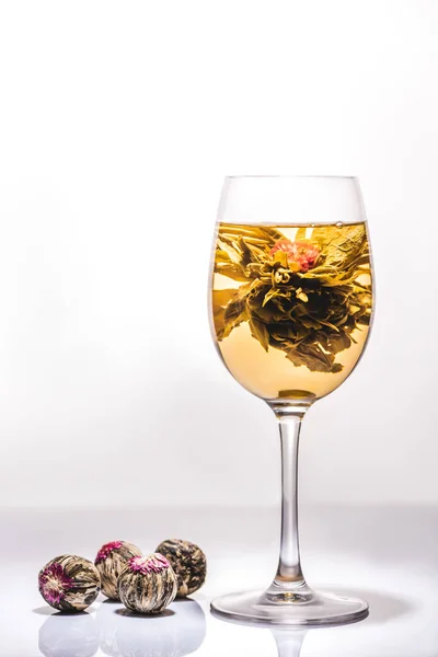 Beautiful glass of chinese flowering tea with tea balls on table — Stock Photo