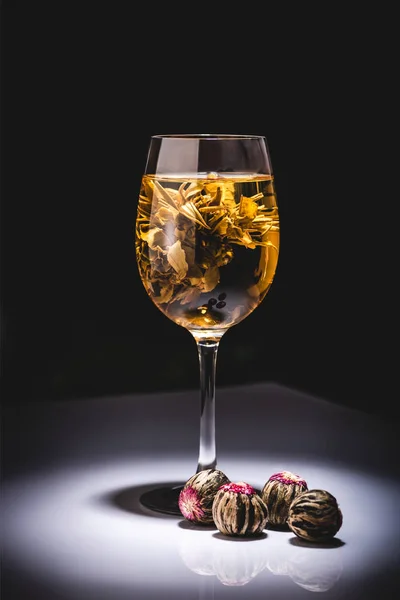 Verre de thé chinois traditionnel à fleurs avec boules de thé sur la table isolé sur noir — Photo de stock
