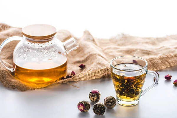 Taza de té chino floreciente, tetera, tela y bolas de té en la mesa - foto de stock