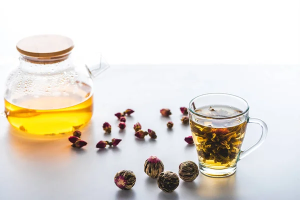Taza de té chino floreciente, tetera y bolas de té en la mesa - foto de stock