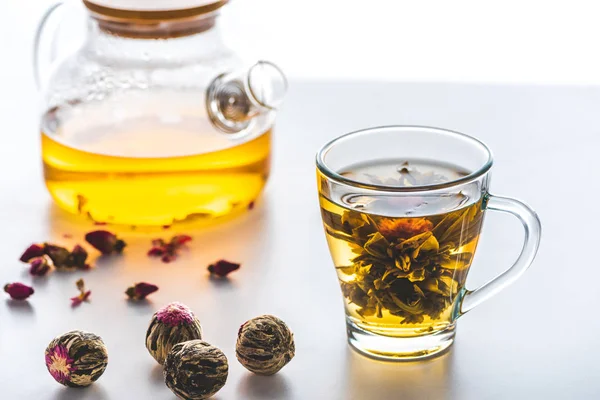 Taza de té floreciente chino con bolas de té en la mesa blanca - foto de stock