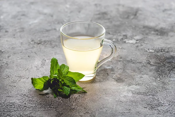Cup of healthy tea with mint on grey surface — Stock Photo