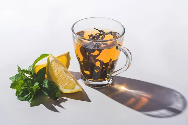 Здоровый чай с лимоном и мятой на белом столе — стоковое фото