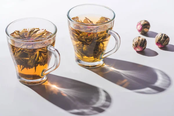 Two cups of chinese flowering tea with tea balls on table — Stock Photo
