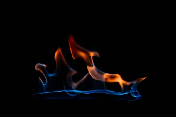 Vue rapprochée de la flamme orange et bleue brûlante sur fond noir — Photo de stock