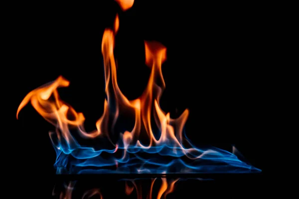 Vue rapprochée de la flamme orange et bleue brûlante sur fond noir — Photo de stock
