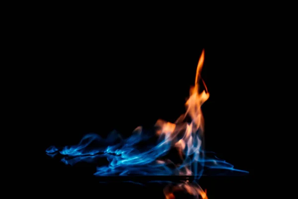 Close up view of burning orange and blue flame on black background — Stock Photo