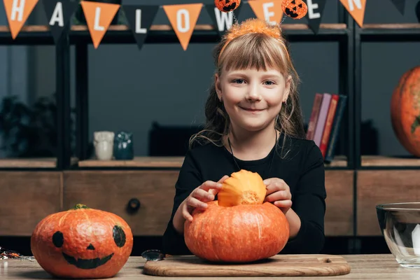 Portrait of adorable child at tabletop with pumpkins for halloween at home — Stock Photo